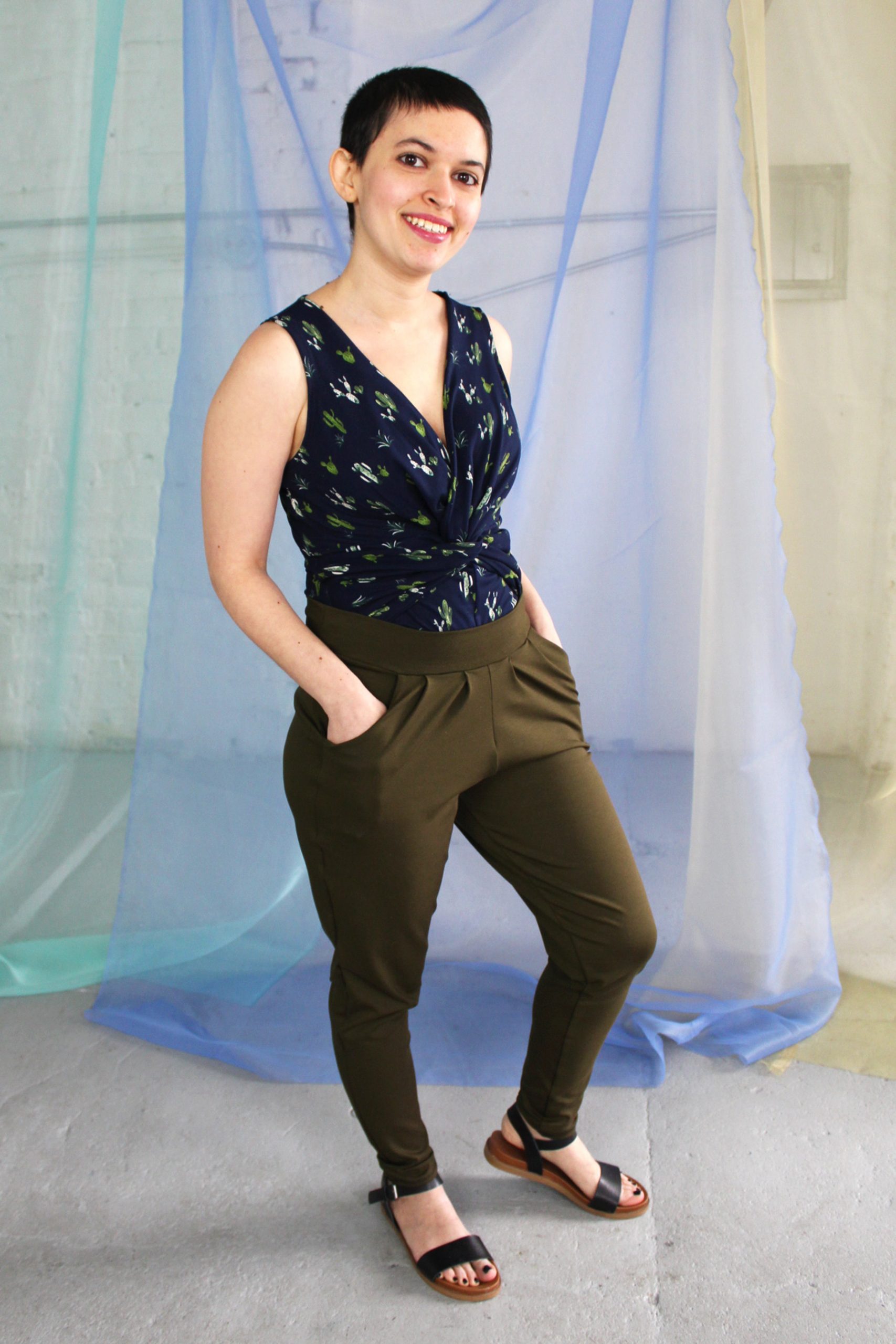 White petite straight size non binary model with brunette pixie haircut wearing navy cactus print tank and olive green pants