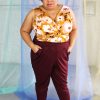Plus size black model with afro + glasses wearing wine maroon pants with pockets and mustard floral twist detail jersey tank