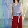 Straight size white brunette tall trans model in maroon red capri pants with pockets and black + white gingham check wrap top