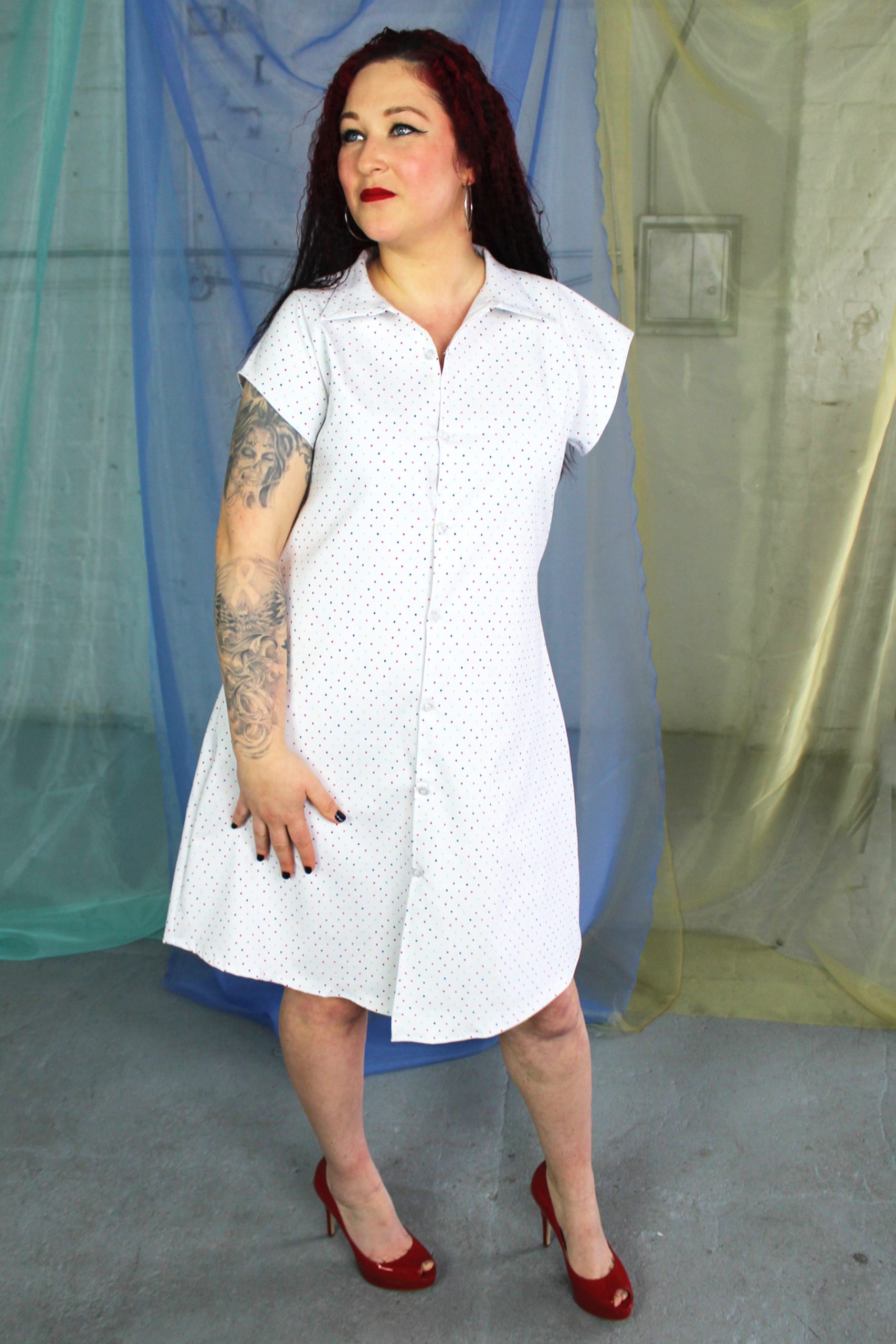 Straight size white female model with one arm modeling white + multi color polka dot button front collared shirt dress