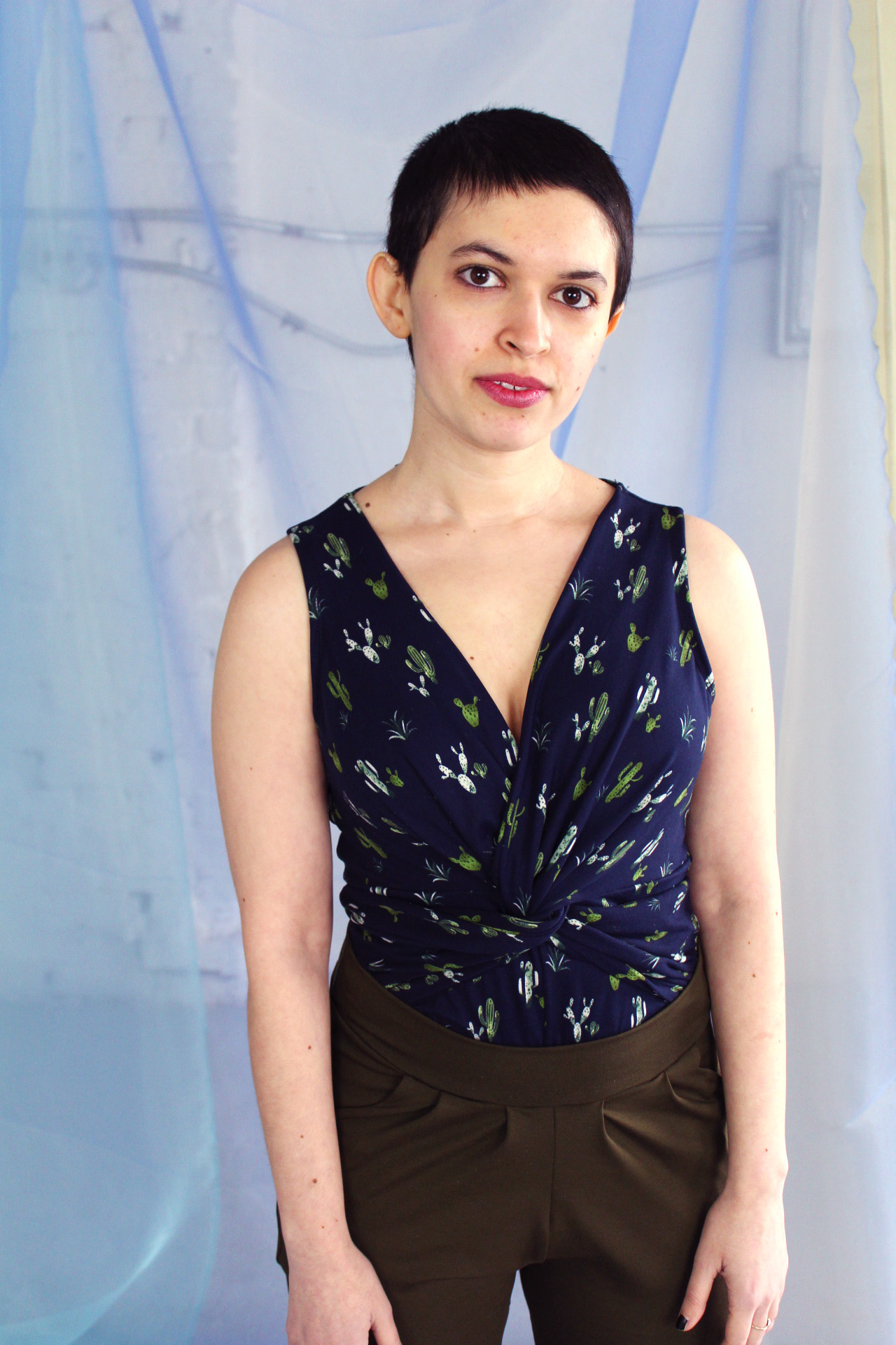Non binary white petite model with short brunette pixie cut modeling navy cactus print twist detail tank top with olive pants