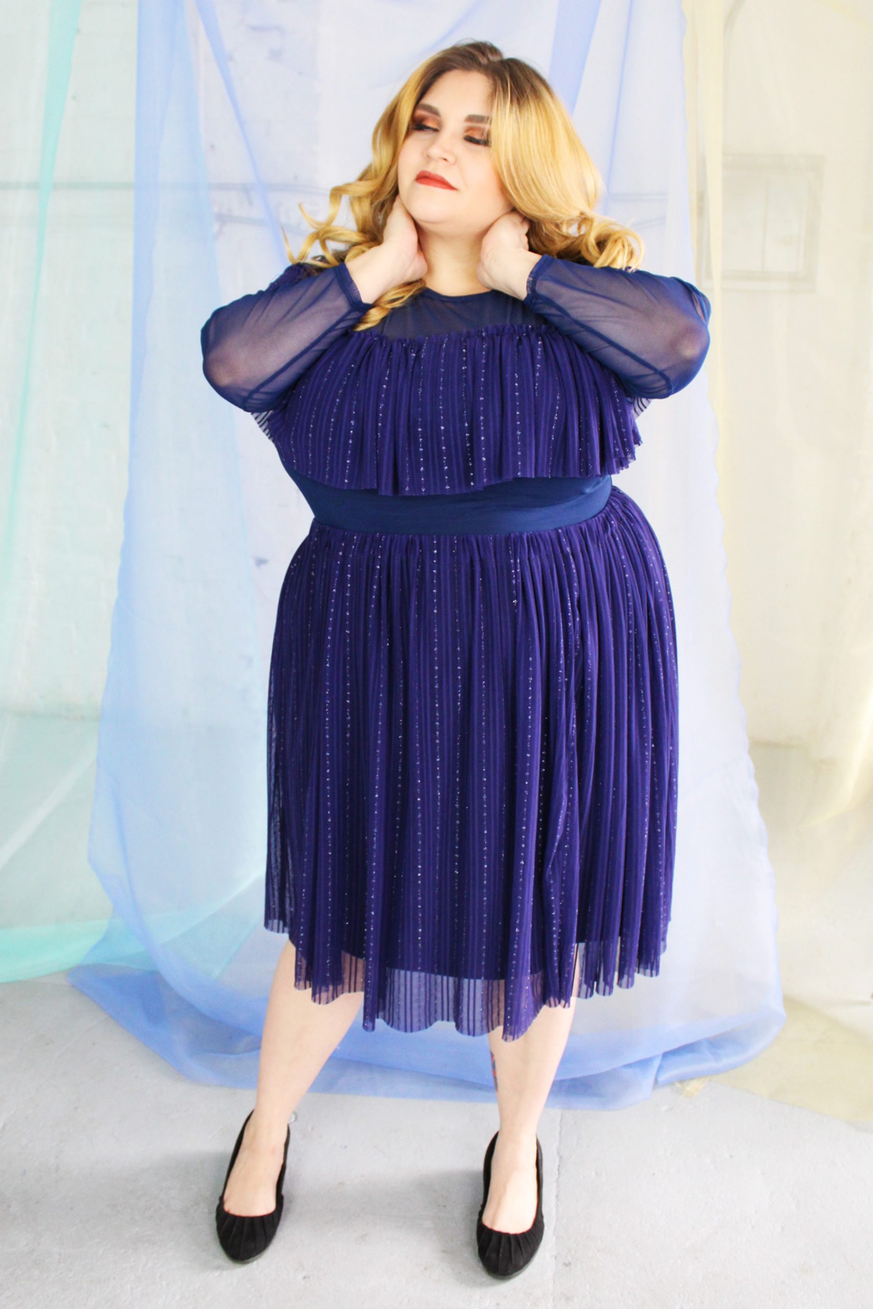 White blonde plus size model wearing navy classic blue mesh skirt smiling and happy, with matching long sleeve ruffle top