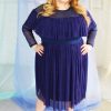 White blonde plus size model wearing navy classic blue mesh high neck long sleeved top with ruffle and matching skirt