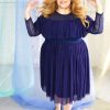 White blonde plus size model wearing navy classic blue mesh high neck long sleeved top with ruffle and matching skirt