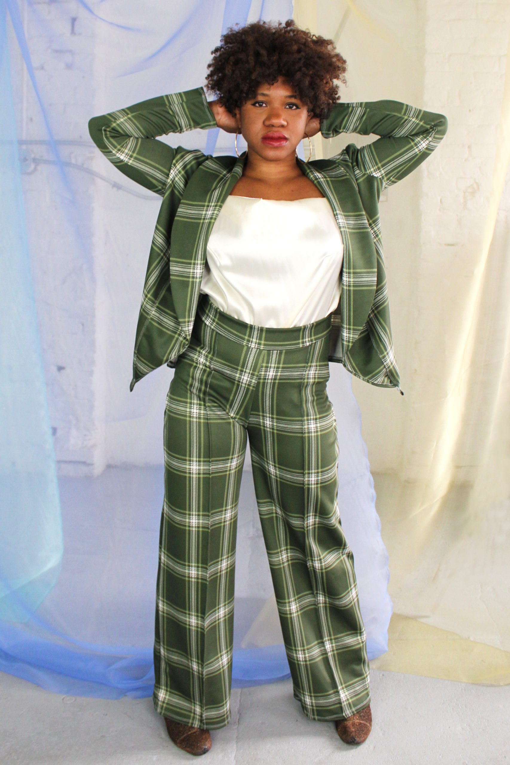 Confident straight size black model with curly short hair wearing green plaid suit and cream satin camisole, handmade in NYC