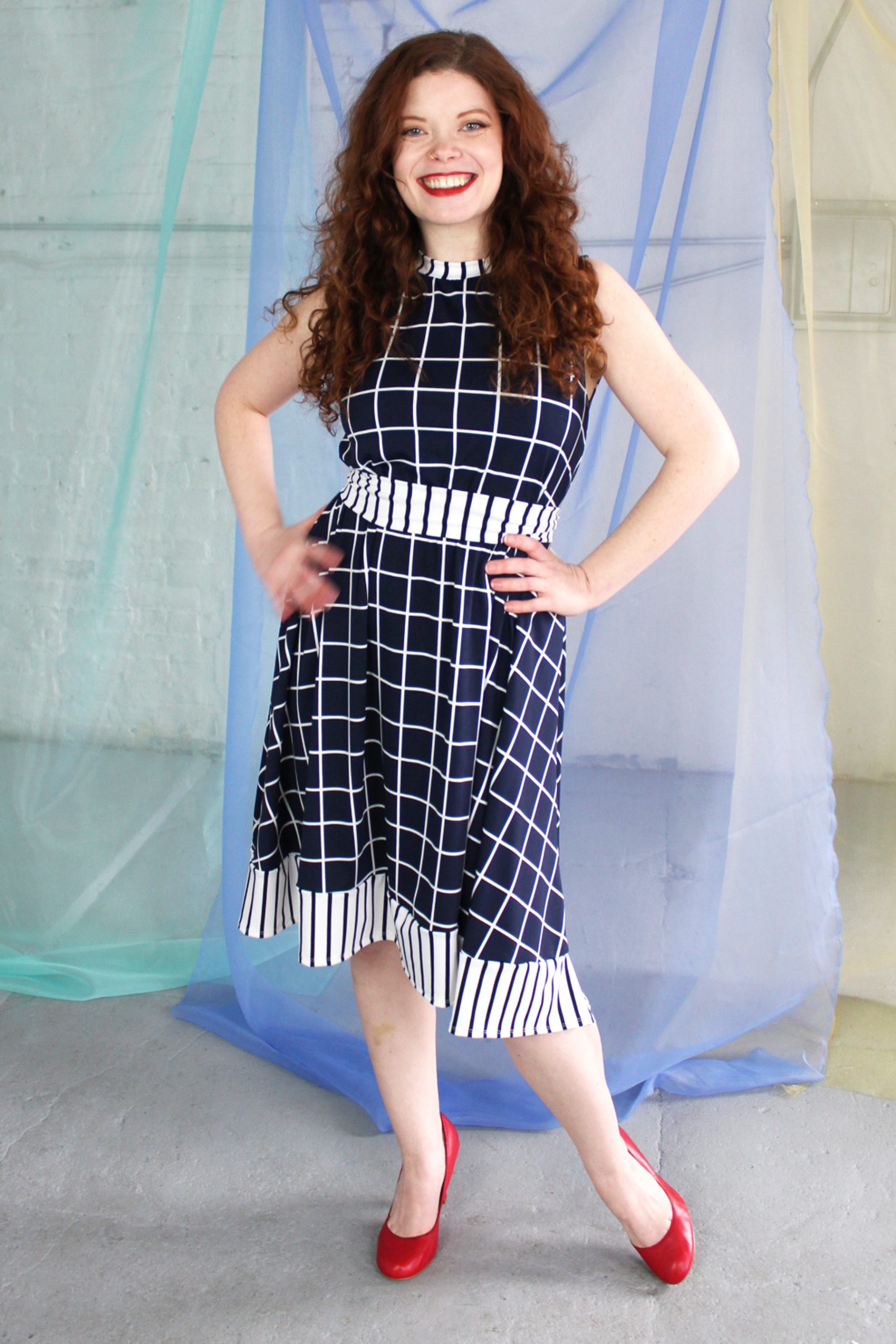 Straight size white redhead model wearing dark navy and white swing dress with striped trim and waist belt, handmade in NYC