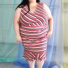 Pink and tan v-neck striped dress with pencil skirt and ruffle hemline modeled by plus size white model with long brown hair.