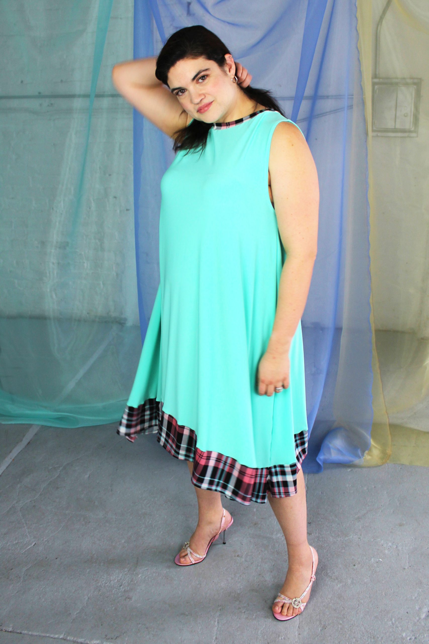 Inbetweenie white brunette model wearing seafoam blue green swing dress with pink plaid trim, ethically handmade in NYC
